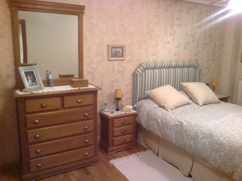 Dormitorio cabecero tapizado de rayas azules y empapelado en beige